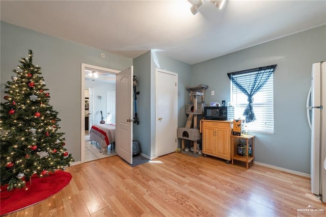 bedroom featuring baseboards, freestanding refrigerator, and light wood-style floors