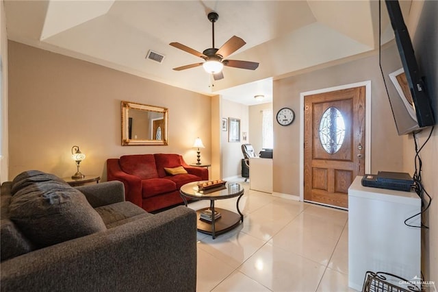 living room with light tile patterned flooring, visible vents, ceiling fan, and baseboards