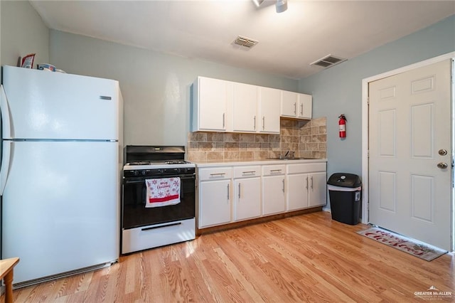 kitchen featuring visible vents, gas range, light countertops, and freestanding refrigerator