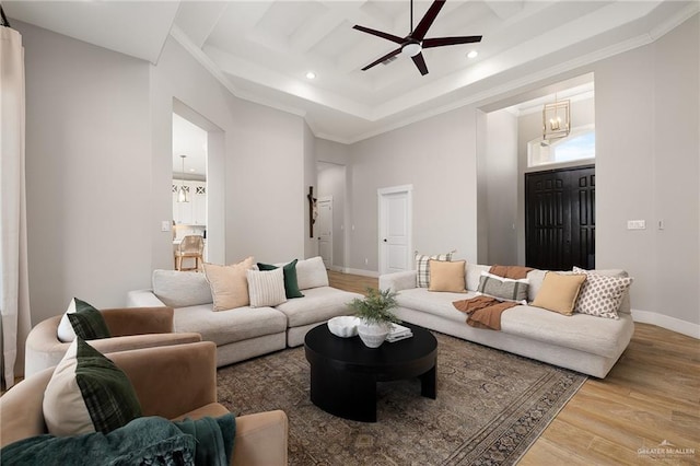 living room featuring hardwood / wood-style floors, ceiling fan, a tray ceiling, a towering ceiling, and crown molding