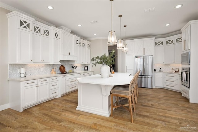 kitchen with decorative light fixtures, white cabinetry, stainless steel appliances, and a center island