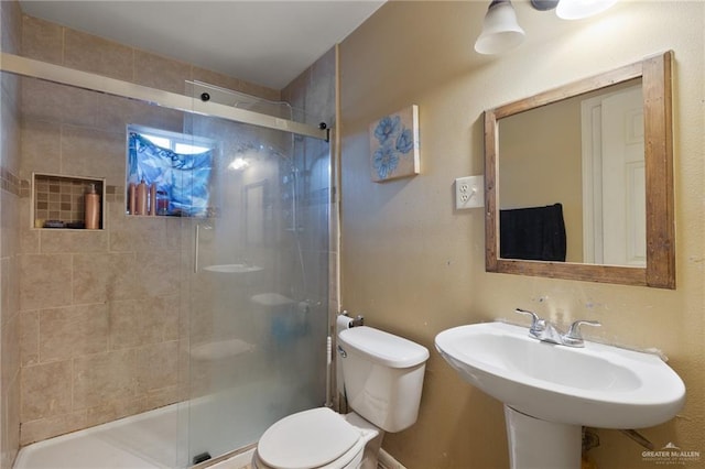 bathroom featuring toilet, a shower with shower door, and sink