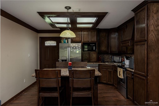 kitchen featuring appliances with stainless steel finishes, light stone counters, pendant lighting, dark hardwood / wood-style floors, and a kitchen island