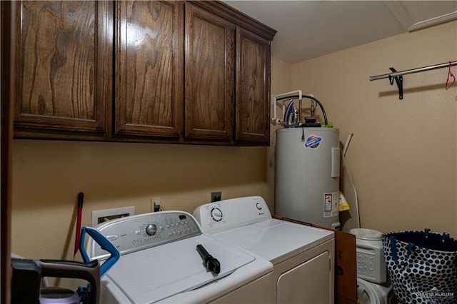 washroom with cabinets, washing machine and dryer, and water heater