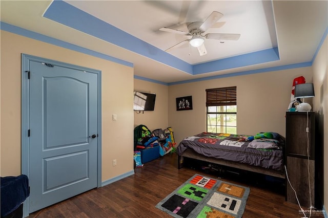 bedroom featuring dark hardwood / wood-style flooring, a raised ceiling, and ceiling fan