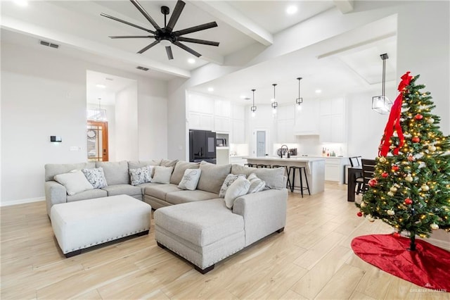 living room with ceiling fan, beamed ceiling, and light hardwood / wood-style floors