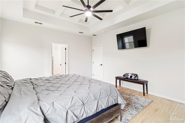 bedroom with hardwood / wood-style floors, ceiling fan, and a tray ceiling