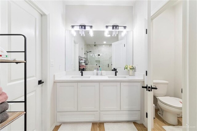 bathroom with a shower with shower door, toilet, wood-type flooring, and vanity