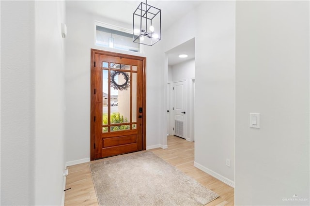 foyer entrance featuring light wood-type flooring and a chandelier