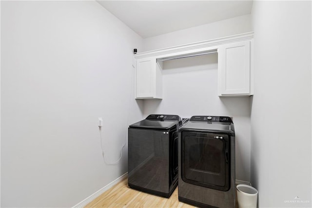 laundry area with cabinets, light hardwood / wood-style floors, and washing machine and clothes dryer