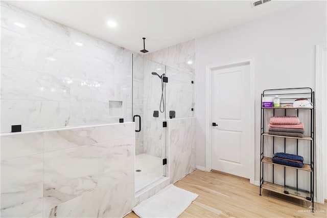 bathroom with hardwood / wood-style flooring and a shower with shower door