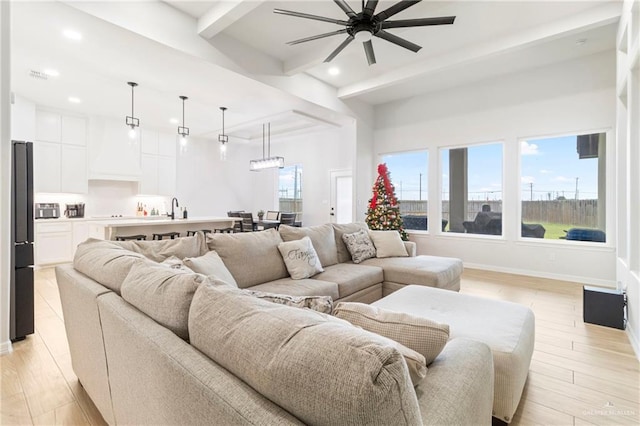 living room featuring ceiling fan, beam ceiling, sink, and light hardwood / wood-style flooring