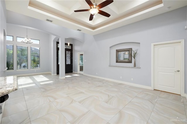 5105 August Ct, Edinburg, TX 78539 - unfurnished room featuring arched walkways, decorative columns, ceiling fan with notable chandelier, a high ceiling, and a raised ceiling