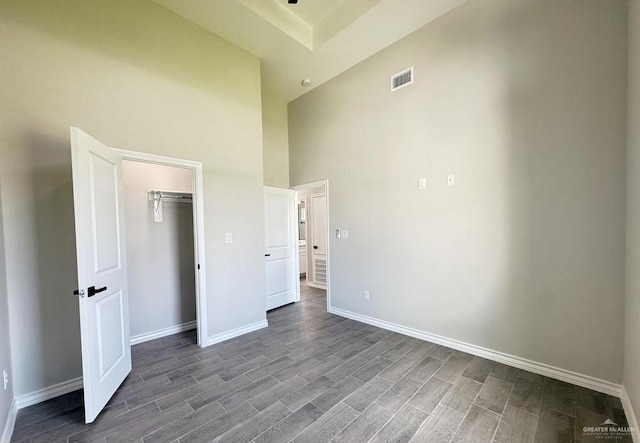 unfurnished bedroom with a closet, hardwood / wood-style floors, and a high ceiling