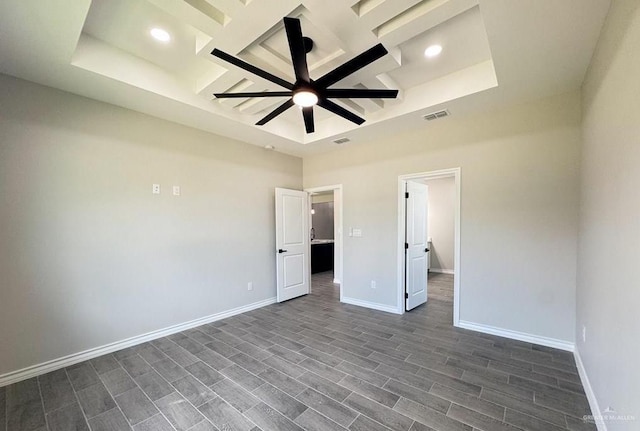 unfurnished bedroom featuring a raised ceiling and dark hardwood / wood-style floors