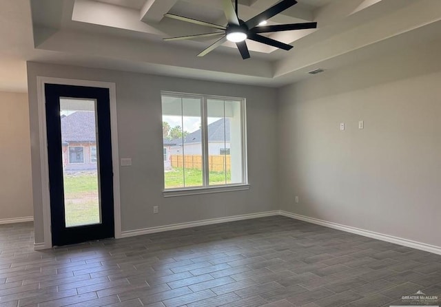 empty room featuring ceiling fan, dark hardwood / wood-style flooring, and a tray ceiling