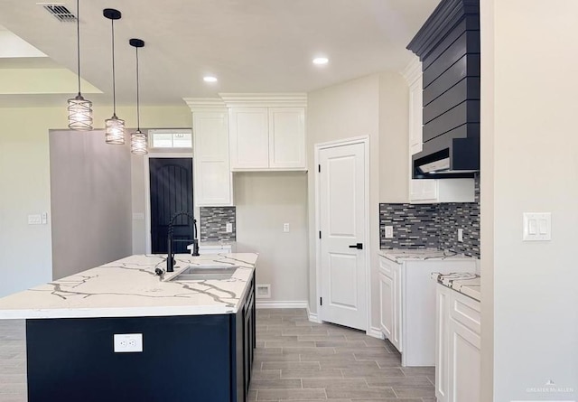 kitchen with white cabinets, sink, and an island with sink