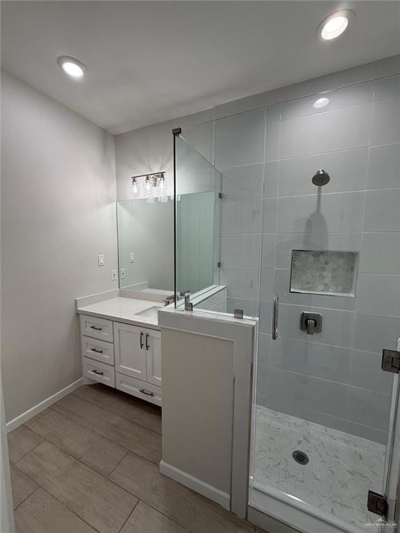 bathroom featuring walk in shower, vanity, and hardwood / wood-style flooring