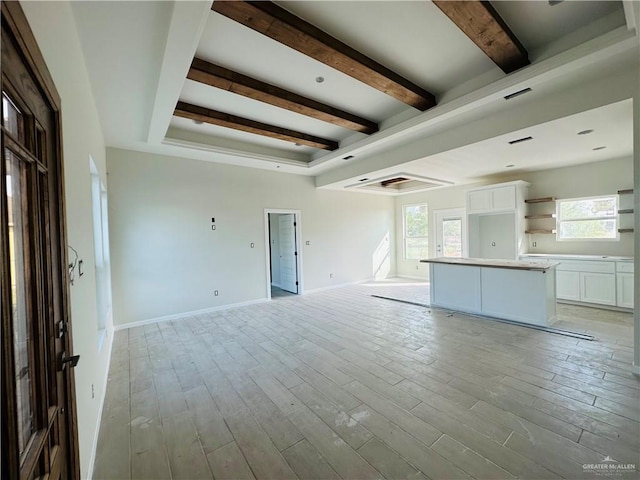 unfurnished living room with beamed ceiling and light hardwood / wood-style flooring