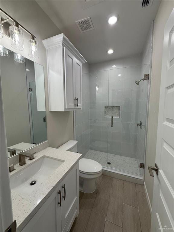 bathroom featuring vanity, toilet, and a shower with shower door