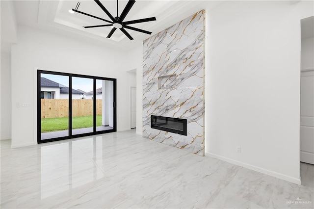 900 N Trinity St, Edinburg, TX 78541 - unfurnished living room featuring marble finish floors, a premium fireplace, a raised ceiling, a ceiling fan, and a towering ceiling