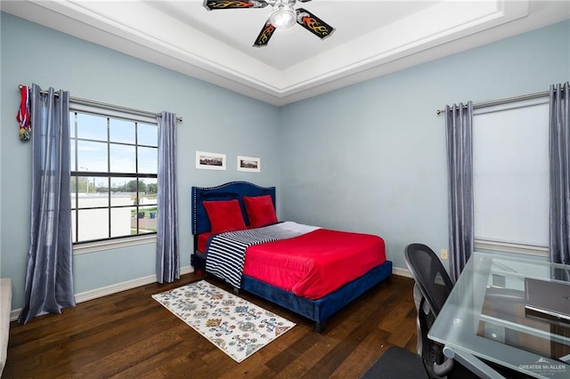 bedroom featuring ceiling fan, dark hardwood / wood-style floors, and a tray ceiling