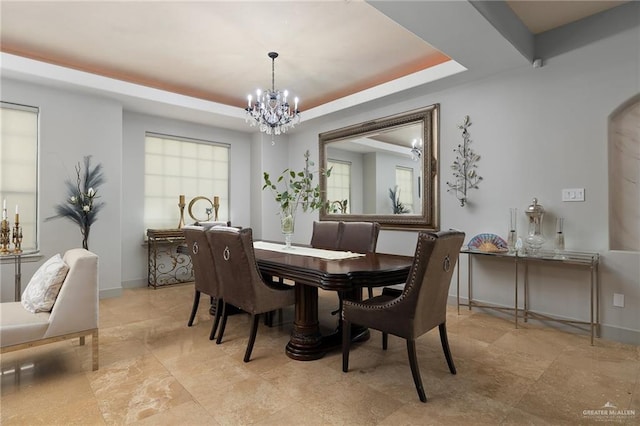 dining area featuring a tray ceiling and a chandelier