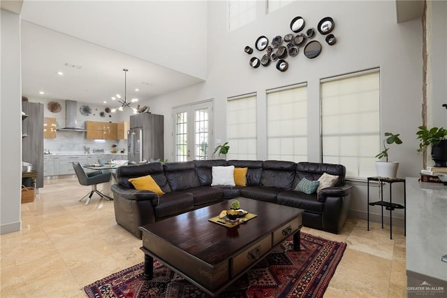 living room with french doors, a towering ceiling, and a notable chandelier