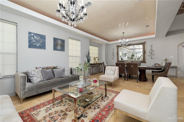 living room with a raised ceiling and an inviting chandelier