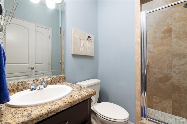 bathroom featuring vanity, a shower with shower door, and toilet