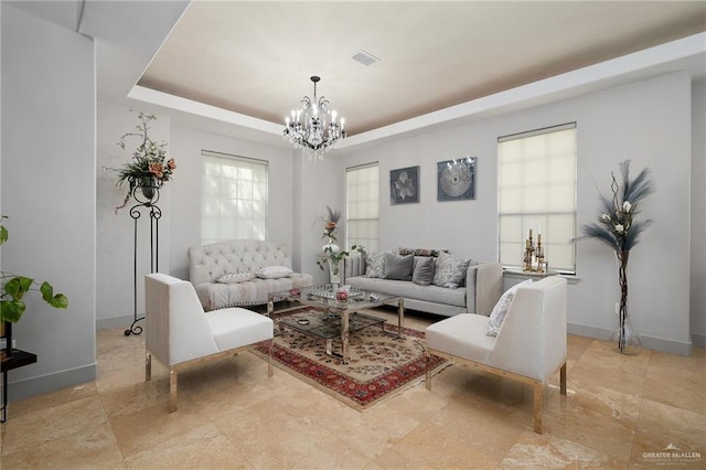 living room featuring a raised ceiling and a notable chandelier