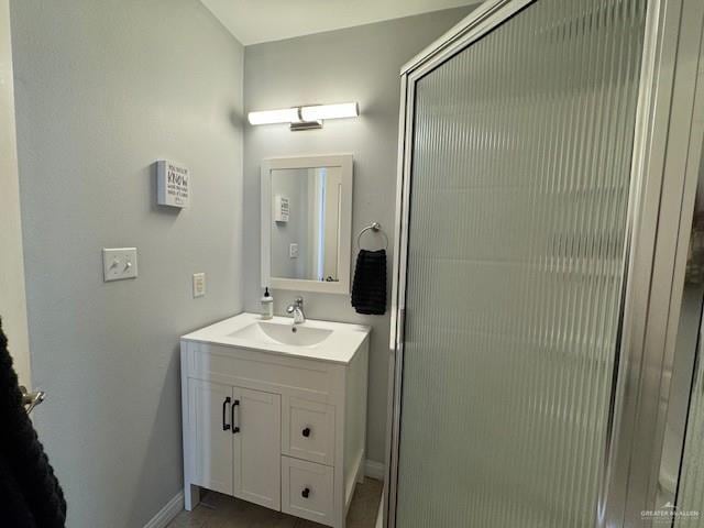 bathroom featuring a shower with door and vanity