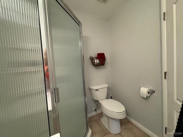 bathroom featuring tile patterned floors, toilet, and a shower with shower door