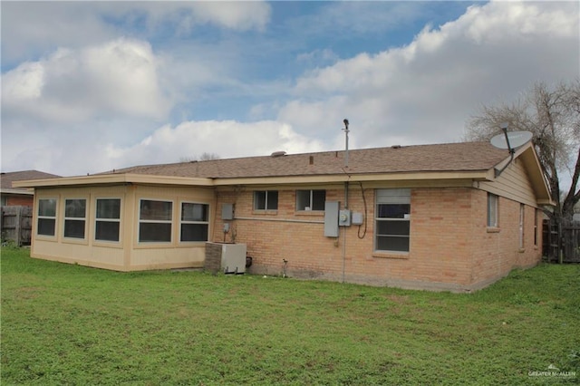 back of house featuring a yard, brick siding, central AC unit, and fence