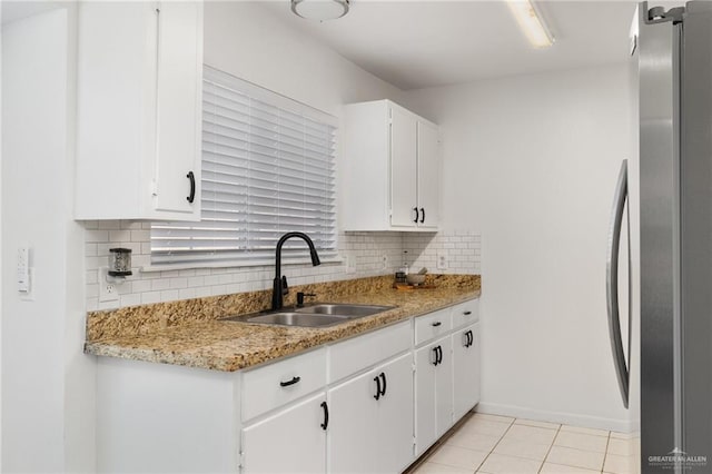 kitchen with sink, white cabinets, light tile patterned floors, decorative backsplash, and stainless steel fridge