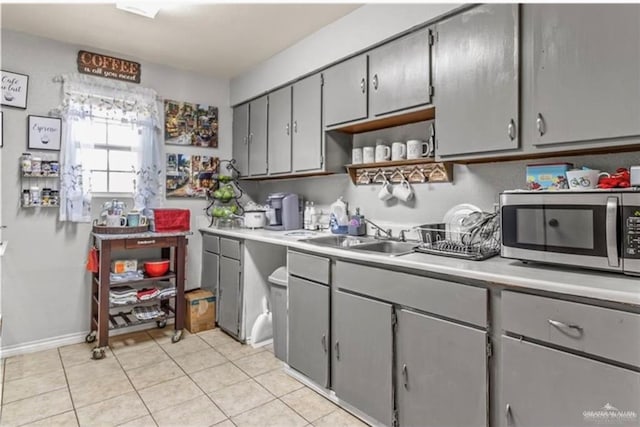 kitchen with gray cabinets, sink, and light tile patterned flooring