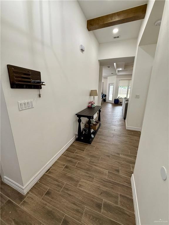 corridor with wood tiled floor, beam ceiling, baseboards, and visible vents