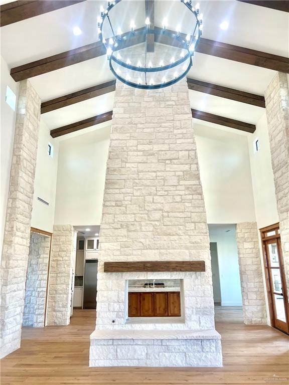 3417 Horizon Trl, Edinburg, TX 78541 - unfurnished living room with high vaulted ceiling, wood finished floors, beamed ceiling, and a stone fireplace