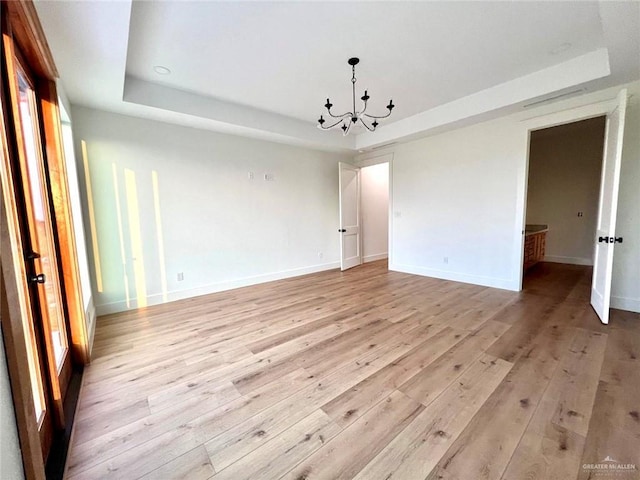 3417 Horizon Trl, Edinburg, TX 78541 - spare room with a tray ceiling, light wood finished floors, and a chandelier