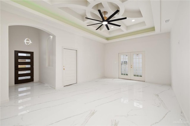 empty room with coffered ceiling, visible vents, a towering ceiling, marble finish floor, and french doors