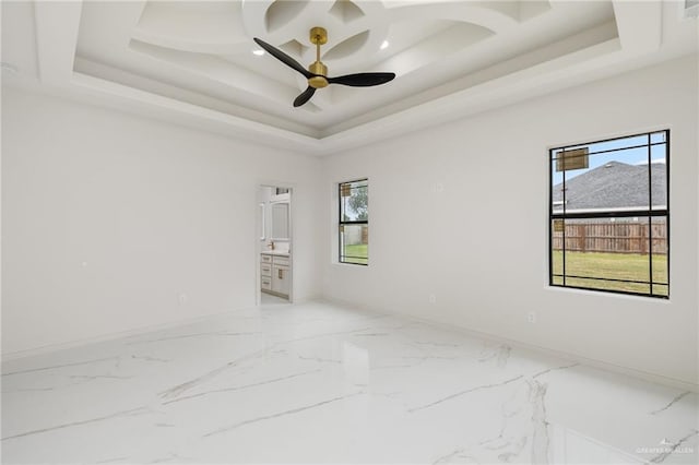 unfurnished room with marble finish floor, a raised ceiling, a ceiling fan, and baseboards