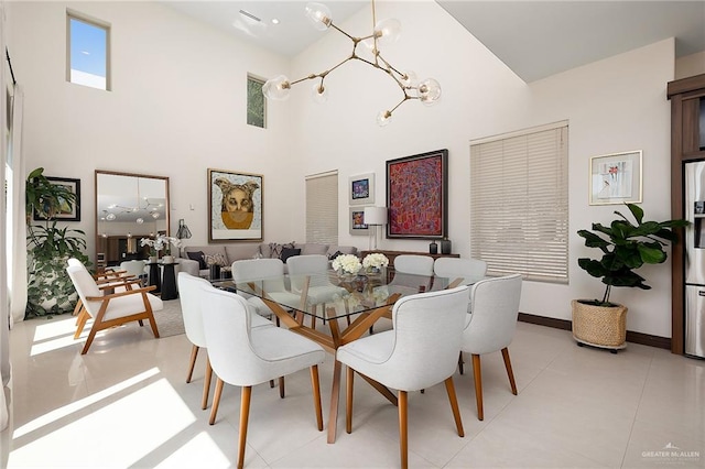 tiled dining area featuring a towering ceiling and a chandelier