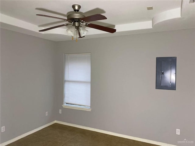 tiled spare room with ceiling fan, electric panel, and a tray ceiling