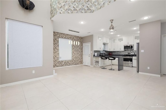 kitchen featuring dark countertops, visible vents, a kitchen bar, white cabinets, and stainless steel appliances