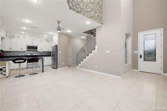 kitchen with light tile patterned floors, a breakfast bar, appliances with stainless steel finishes, dark countertops, and backsplash