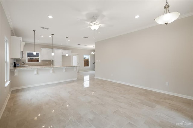 unfurnished living room with baseboards, ornamental molding, visible vents, and a ceiling fan