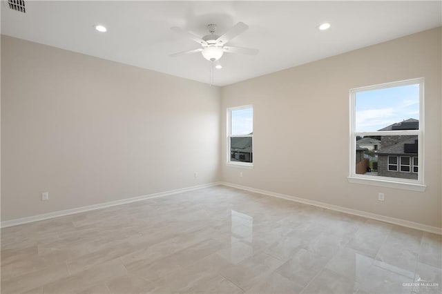 spare room featuring a healthy amount of sunlight, visible vents, ceiling fan, and baseboards