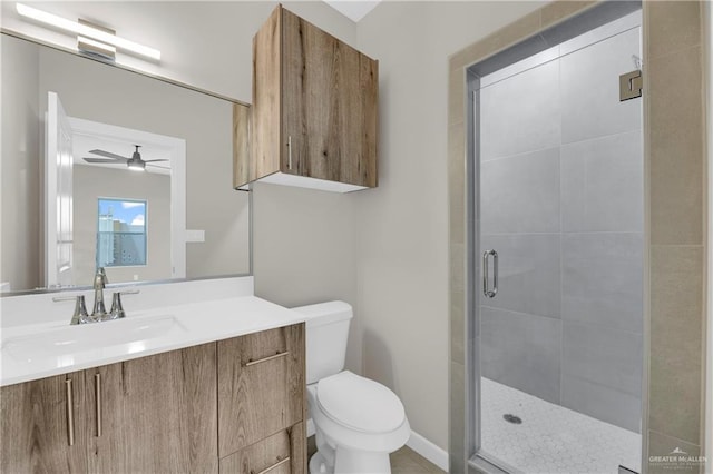 bathroom featuring ceiling fan, vanity, a shower with shower door, and toilet