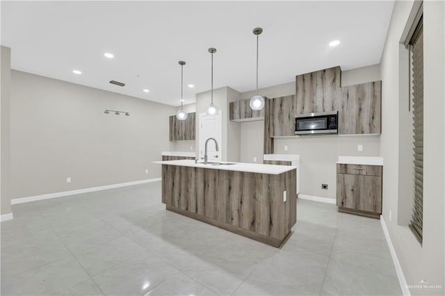 kitchen with a center island with sink, sink, and hanging light fixtures