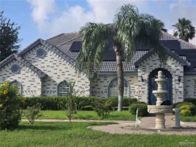 2210 W Monte Cristo Rd W, Edinburg, TX 78541 - view of front of property featuring roof mounted solar panels, a front lawn, and brick siding